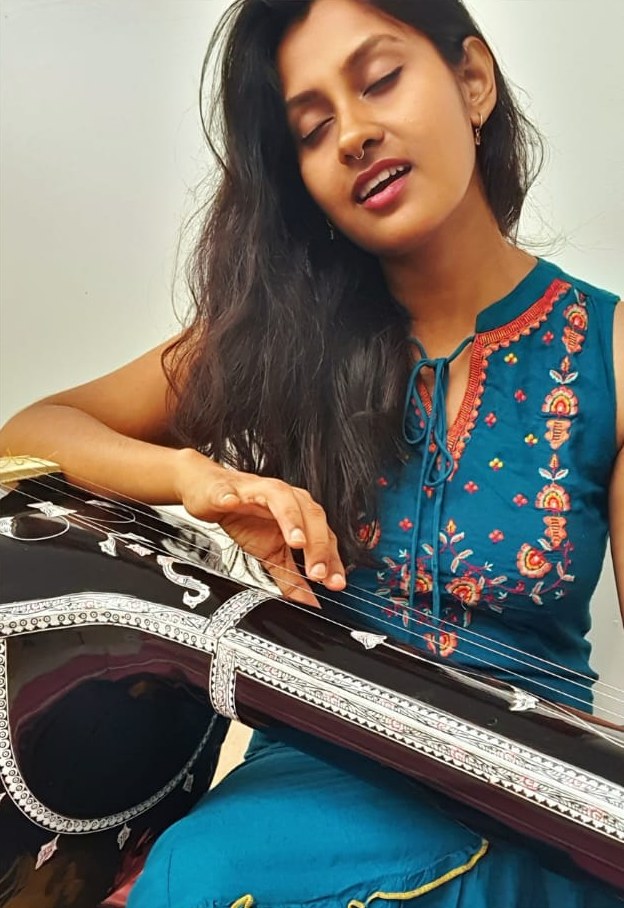 Aritri singing with eyes closed, playing a tanpura